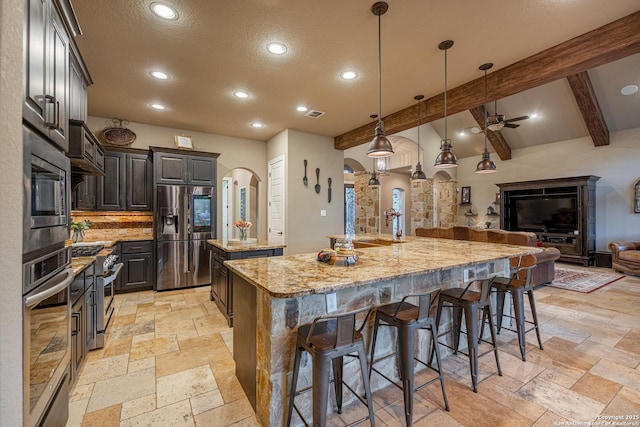1040 Glenwood, Bulverde, TX 78163 - kitchen with stainless steel appliances, a spacious island, stone tile flooring, ceiling fan, and arched walkways