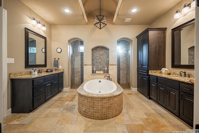 1040 Glenwood, Bulverde, TX 78163 - bathroom with stone tile floors, a garden tub, two vanities, recessed lighting, and a textured ceiling