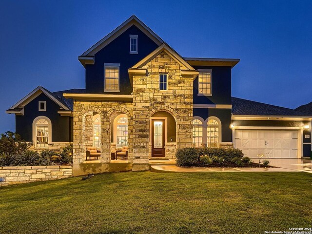 view of front of property with stone siding, a front yard, an attached garage, stucco siding, and driveway