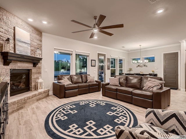 living room with a ceiling fan, crown molding, a chandelier, a fireplace, and light wood-style flooring