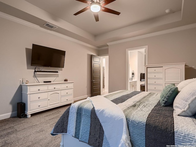 bedroom with a tray ceiling, light colored carpet, baseboards, ceiling fan, and ensuite bath