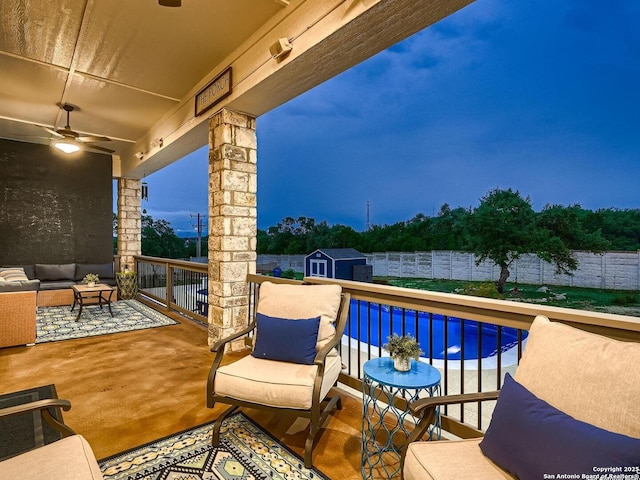 view of patio with a storage unit, an outdoor structure, ceiling fan, an outdoor hangout area, and a fenced backyard
