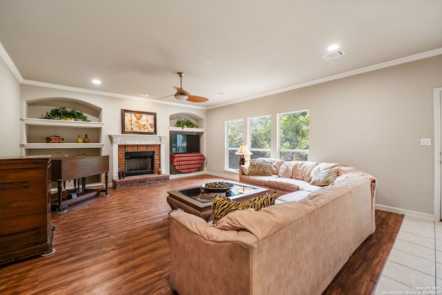 38 Atwell, San Antonio, TX 78254 - living area featuring ornamental molding, ceiling fan, built in shelves, a brick fireplace, and wood finished floors