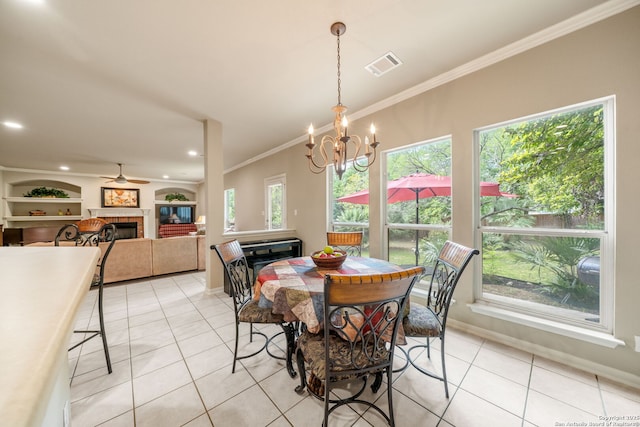 38 Atwell, San Antonio, TX 78254 - dining area featuring a tiled fireplace, light tile patterned flooring, crown molding, a chandelier, and baseboards