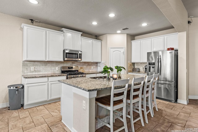 1002 Faith Rnch, San Antonio, TX 78245 - kitchen featuring appliances with stainless steel finishes, baseboards, a center island with sink, tasteful backsplash, and recessed lighting