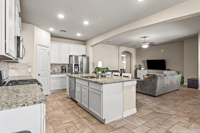 1002 Faith Rnch, San Antonio, TX 78245 - kitchen featuring appliances with stainless steel finishes, a sink, arched walkways, ceiling fan, and decorative backsplash