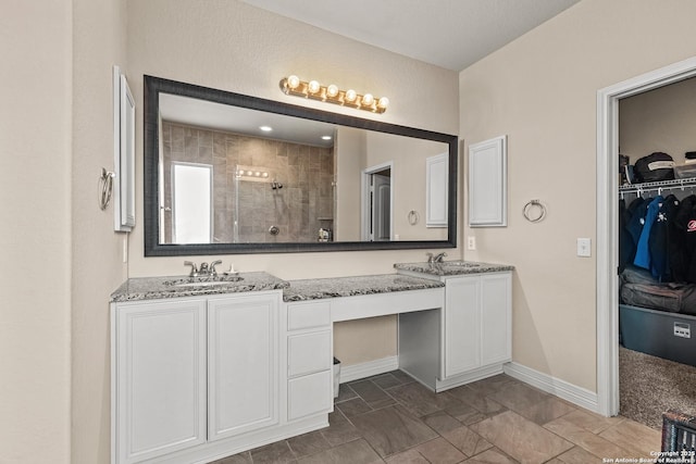 1002 Faith Rnch, San Antonio, TX 78245 - bathroom featuring double vanity, a stall shower, a walk in closet, and baseboards