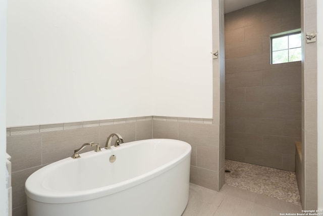 full bath with a soaking tub, a walk in shower, tile walls, and tile patterned flooring