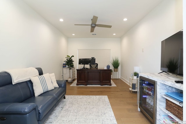 living area featuring beverage cooler, light wood-style flooring, a ceiling fan, recessed lighting, and baseboards
