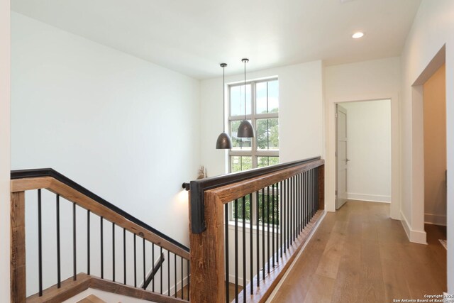 hallway with wood finished floors, baseboards, recessed lighting, and an upstairs landing