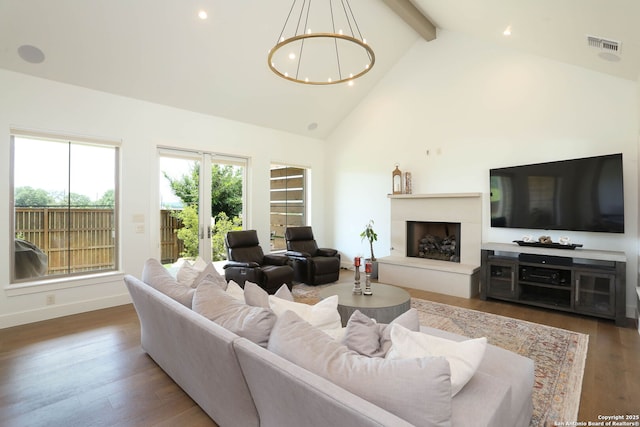 living room with a chandelier, beam ceiling, high vaulted ceiling, recessed lighting, and a fireplace with raised hearth