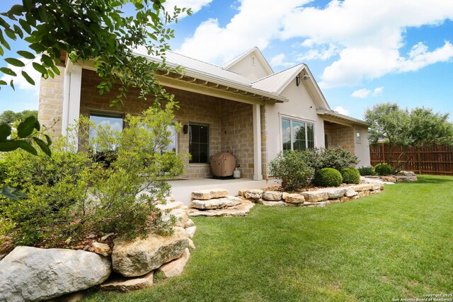back of property featuring stone siding, metal roof, and a patio area