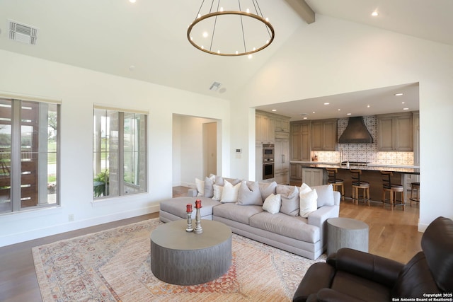 living room featuring a chandelier, light wood-type flooring, high vaulted ceiling, recessed lighting, and baseboards