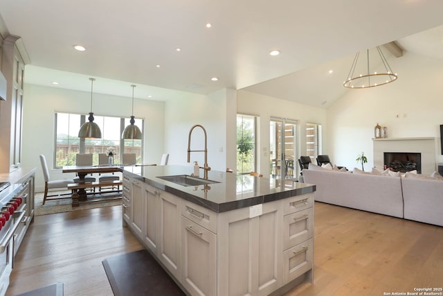 kitchen with a sink, dark countertops, recessed lighting, plenty of natural light, and a center island with sink