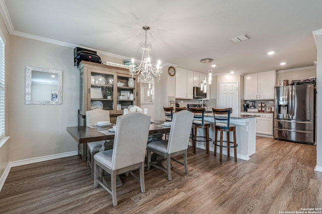 6136 Sunflower, San Antonio, TX 78244 - dining room with wood finished floors, a chandelier, crown molding, baseboards, and recessed lighting