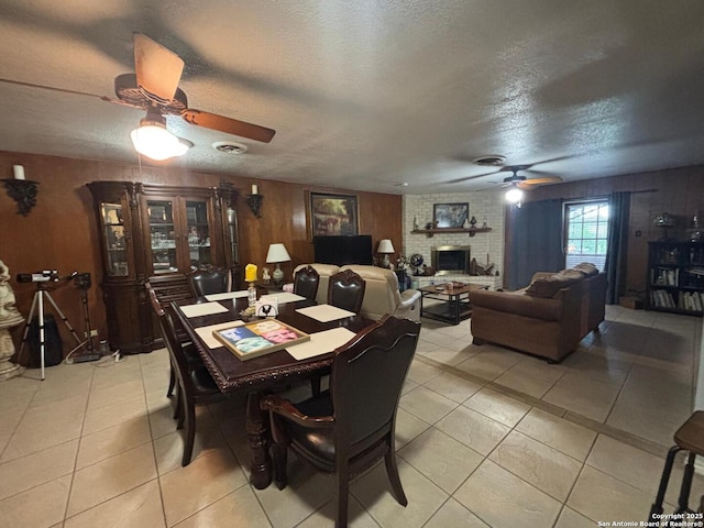3802 Quiver, San Antonio, TX 78238 - dining area with ceiling fan, wooden walls, a textured ceiling, light tile patterned floors, and a fireplace