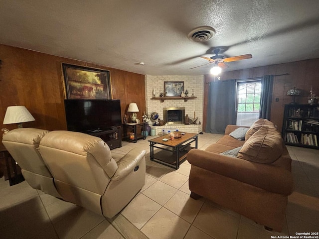 3802 Quiver, San Antonio, TX 78238 - living room with wooden walls, ceiling fan, light tile patterned floors, a textured ceiling, and a brick fireplace