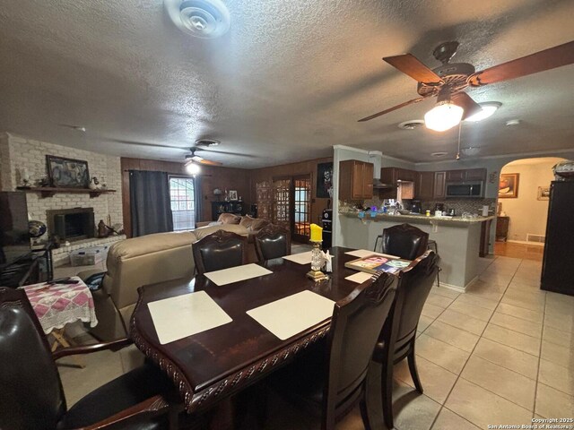 3802 Quiver, San Antonio, TX 78238 - dining area featuring ceiling fan, a textured ceiling, arched walkways, light tile patterned floors, and a brick fireplace