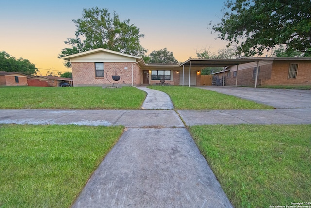 ranch-style home with brick siding, a front lawn, driveway, and an attached carport