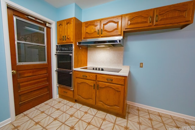 kitchen featuring black appliances, brown cabinets, under cabinet range hood, light countertops, and decorative backsplash
