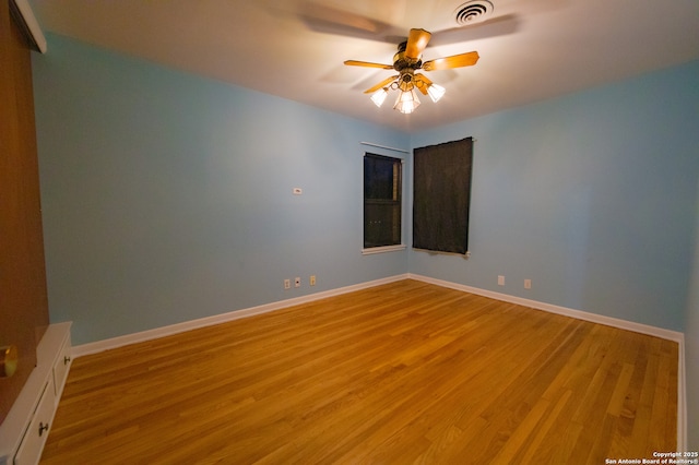 spare room featuring light wood finished floors, a ceiling fan, and baseboards