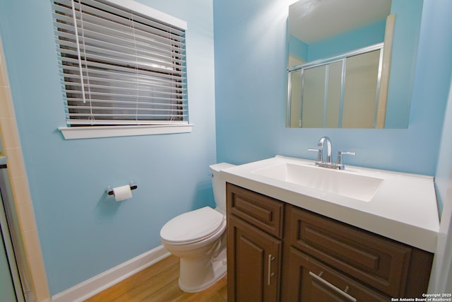 bathroom featuring a shower stall, wood finished floors, toilet, vanity, and baseboards
