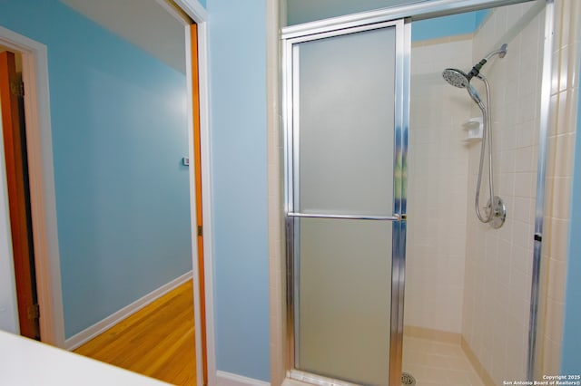 full bath with a shower stall, wood finished floors, and baseboards