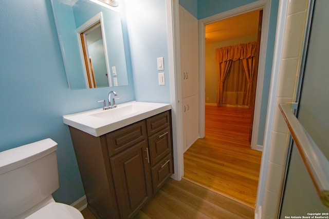 bathroom featuring wood finished floors, toilet, and vanity