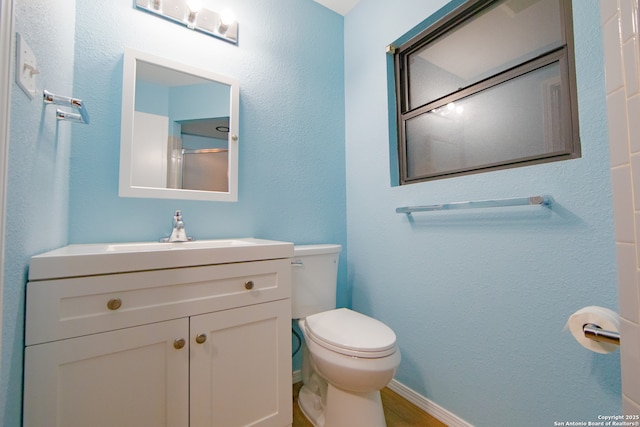 bathroom featuring toilet, vanity, and wood finished floors