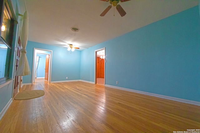 empty room featuring a ceiling fan, light wood-type flooring, and baseboards
