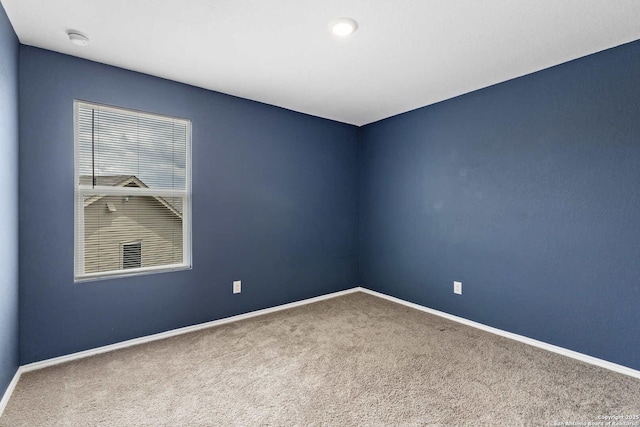 carpeted spare room with baseboards and a smoke detector