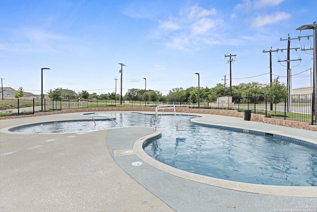 community pool with fence and a patio area