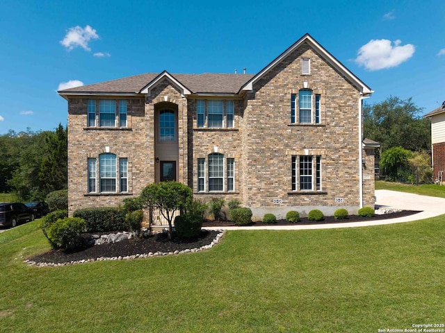 traditional-style home featuring a front lawn and brick siding
