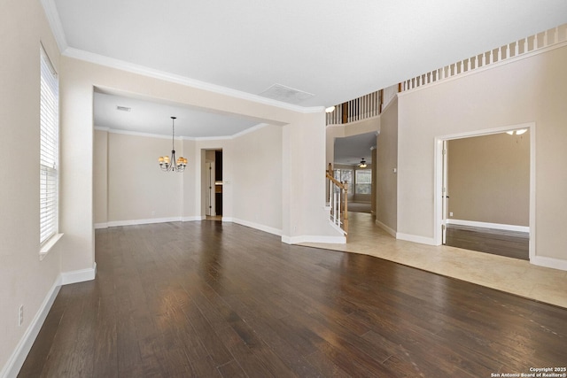 unfurnished living room featuring a chandelier, wood finished floors, crown molding, stairs, and baseboards