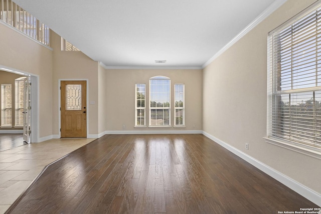 entrance foyer featuring wood-type flooring, baseboards, and crown molding