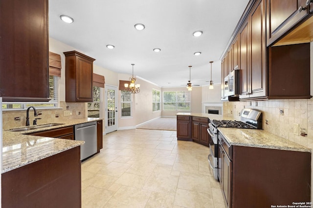 kitchen featuring appliances with stainless steel finishes, a sink, baseboards, a chandelier, and a peninsula