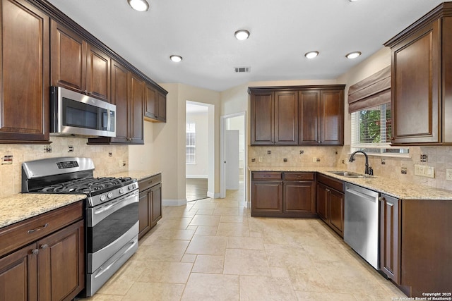 kitchen with appliances with stainless steel finishes, a sink, backsplash, and recessed lighting