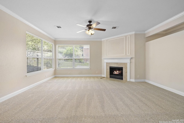 unfurnished living room with crown molding, a ceiling fan, baseboards, light colored carpet, and a tiled fireplace