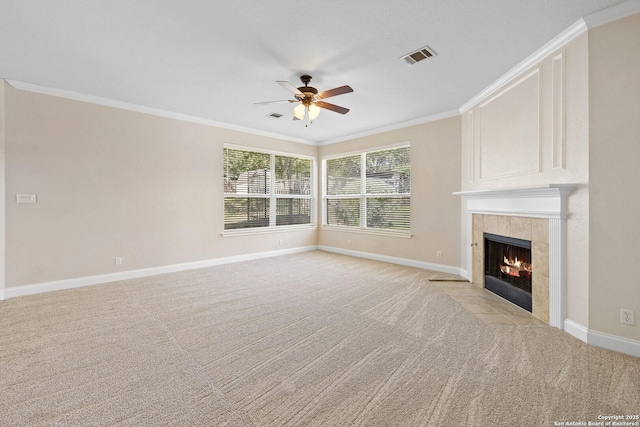 unfurnished living room with a ceiling fan, crown molding, light colored carpet, baseboards, and a tiled fireplace