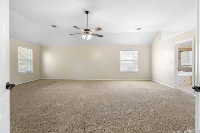carpeted spare room with lofted ceiling, a ceiling fan, plenty of natural light, and baseboards