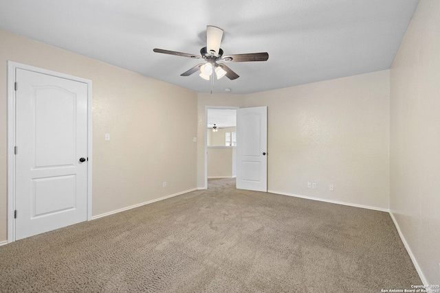 unfurnished room with carpet floors, a ceiling fan, and baseboards