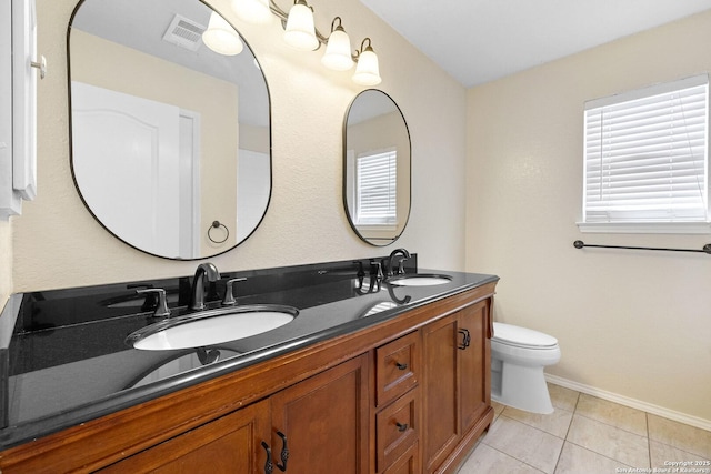 full bath with toilet, double vanity, tile patterned flooring, and baseboards