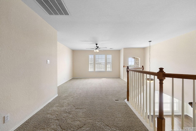 hallway featuring carpet, a textured wall, an upstairs landing, and baseboards