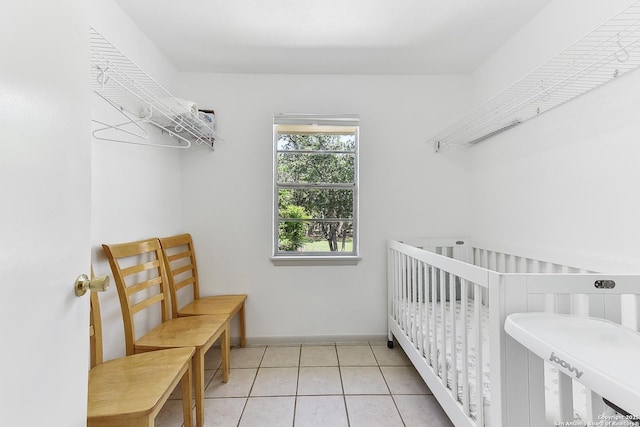 bedroom with light tile patterned floors, baseboards, and a nursery area