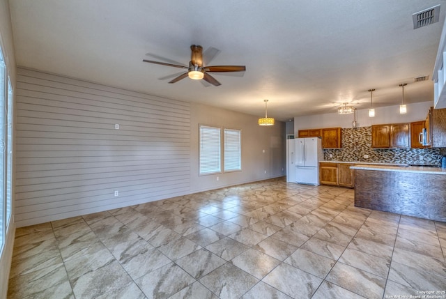 120 W Brazos, Uvalde, TX 78801 - kitchen with freestanding refrigerator, brown cabinetry, a ceiling fan, and pendant lighting