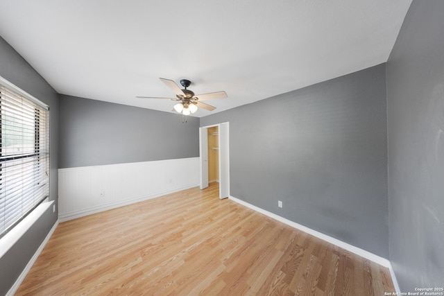 8201 Bluff Bnd, San Antonio, TX 78250 - unfurnished room with wood finished floors, ceiling fan, a wainscoted wall, and baseboards