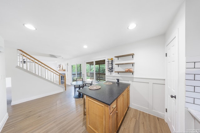 8201 Bluff Bnd, San Antonio, TX 78250 - kitchen with light wood-type flooring, open shelves, a breakfast bar, wainscoting, and dark countertops