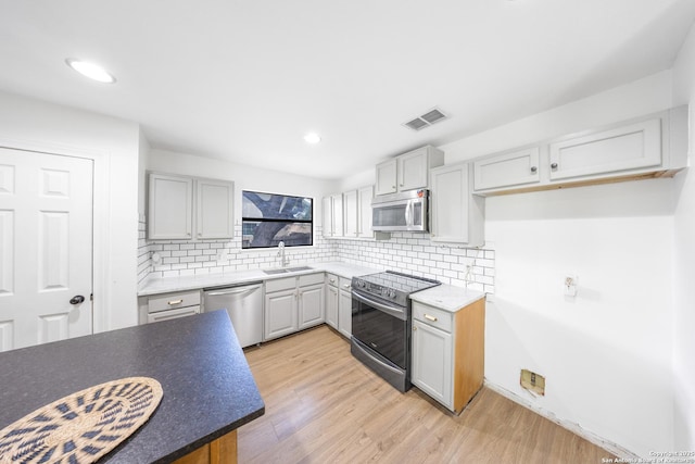 8201 Bluff Bnd, San Antonio, TX 78250 - kitchen featuring stainless steel appliances, a sink, light wood finished floors, backsplash, and recessed lighting