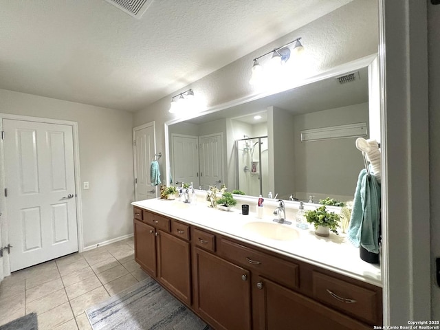 bathroom featuring a stall shower, tile patterned flooring, double vanity, and baseboards