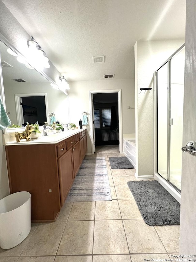 full bath with a shower stall, double vanity, tile patterned floors, and a textured ceiling
